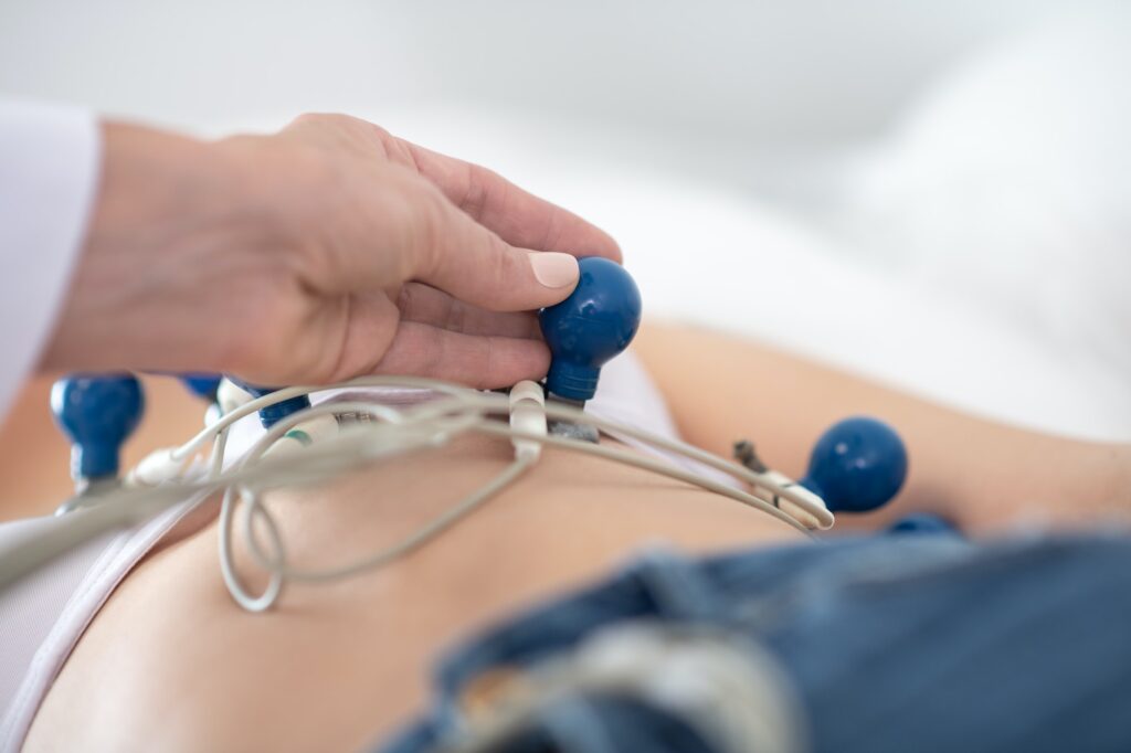 Doctor in white robe making ekg to the patient